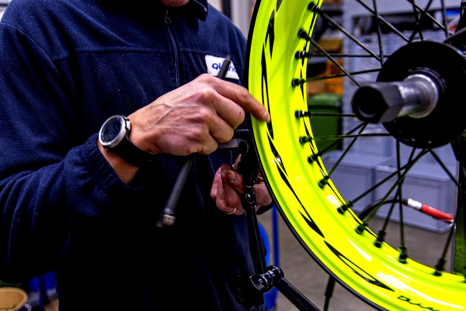 Technician manually assembling and adjusting a Pisces spoked wheel